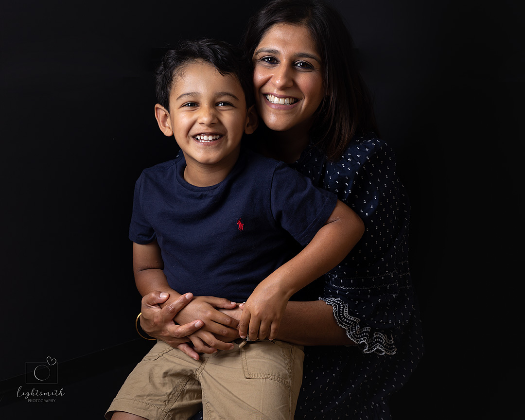 a studio portrait of a mother and her son, both smiling