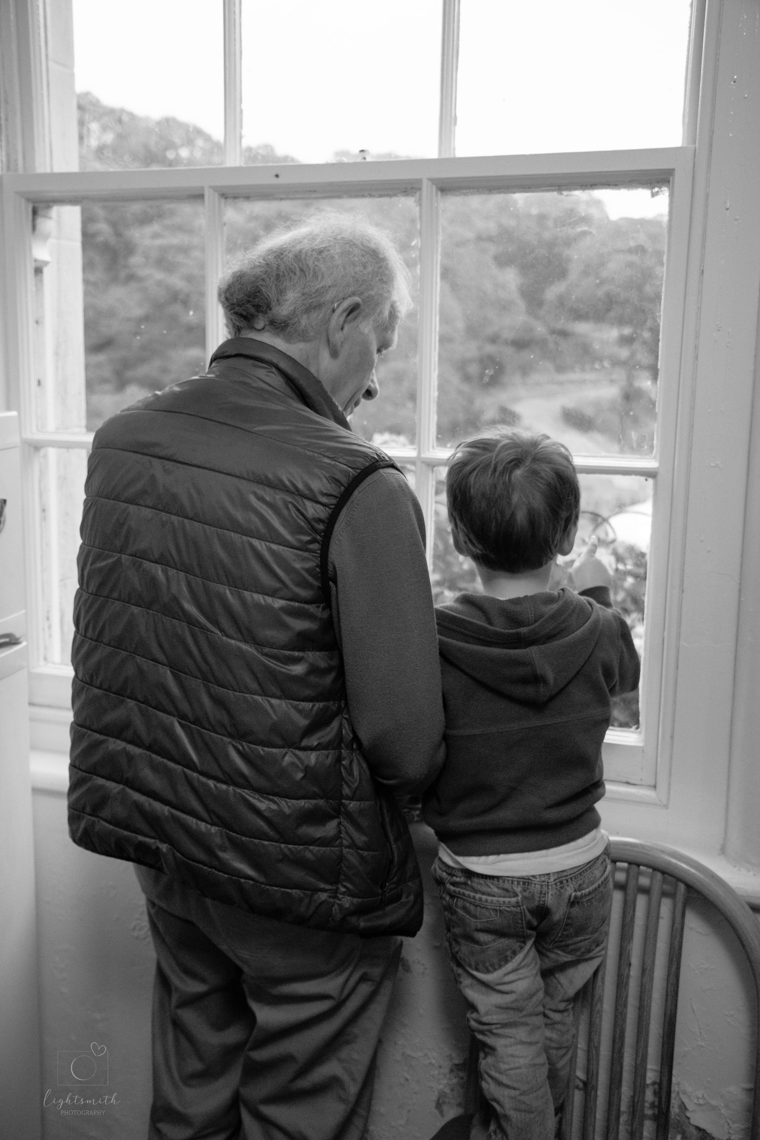 a grandfather looking out the window with his grandson
