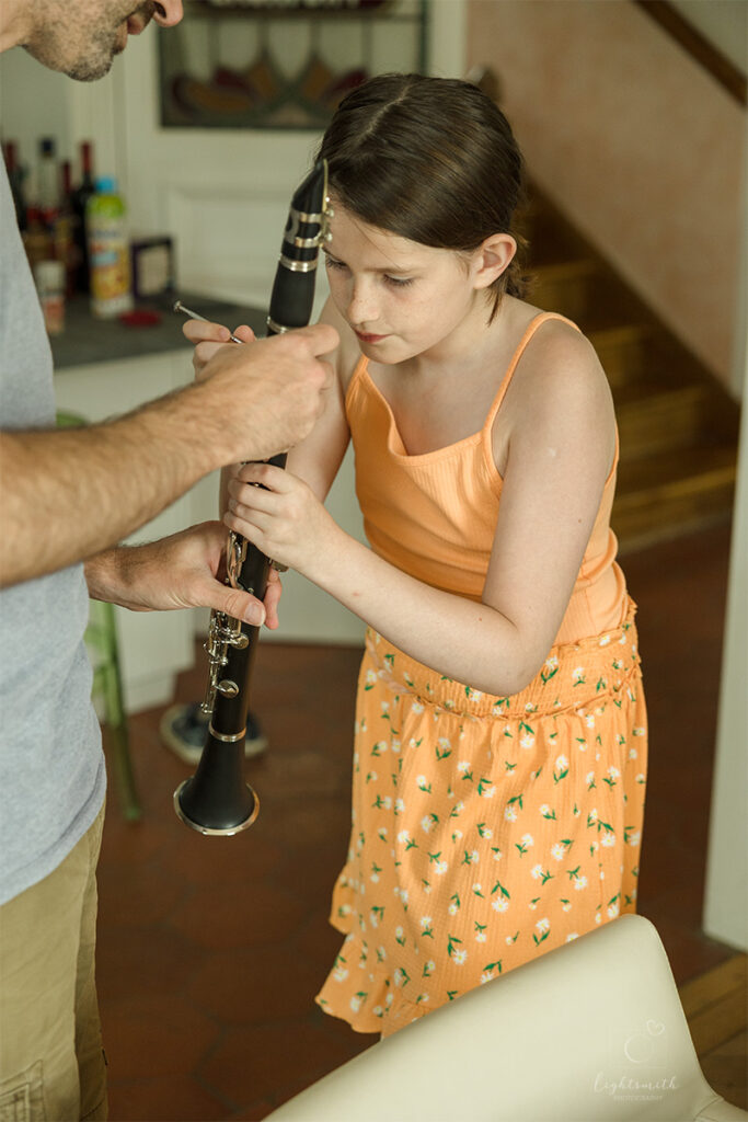 a girl cleaning her clarinet, her dad is helping her
