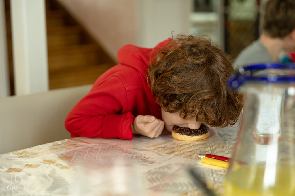a boy face planting in a chocolate doughnut